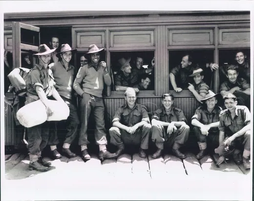 Troops assembled beside a troop train before embarkation.